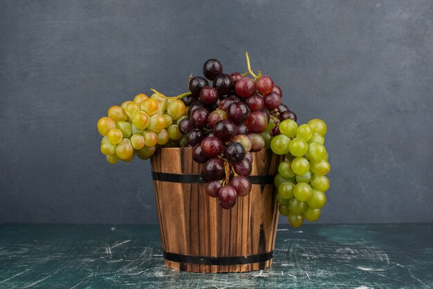 Un racimo de uvas verdes y negras sobre la mesa de mármol.