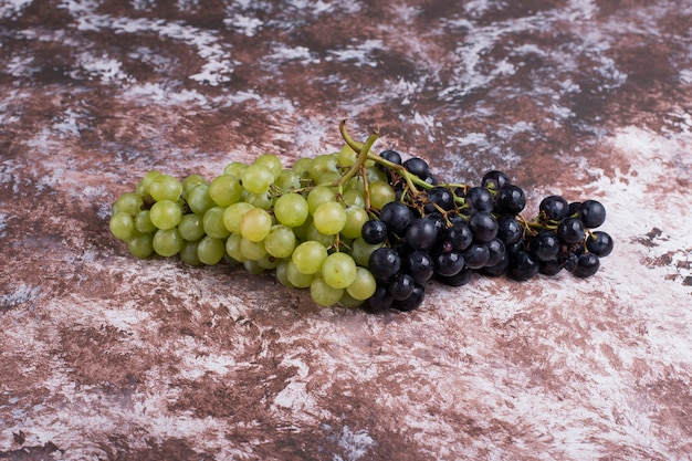 Un racimo de uvas verdes y rojas en el mármol.