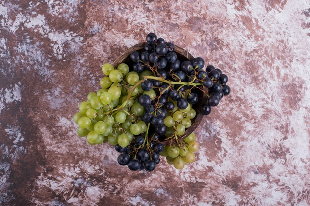 Un racimo de uvas verdes y rojas en el mármol.