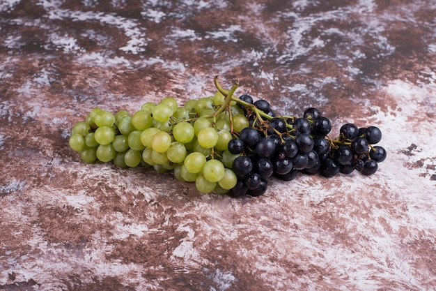 Foto gratuita un racimo de uvas verdes y rojas sobre la mesa