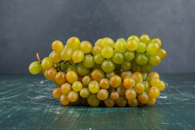 Racimo de uvas verdes sobre mesa de mármol.