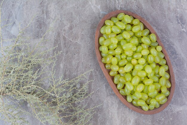 Racimo de uvas verdes en un tazón de madera.