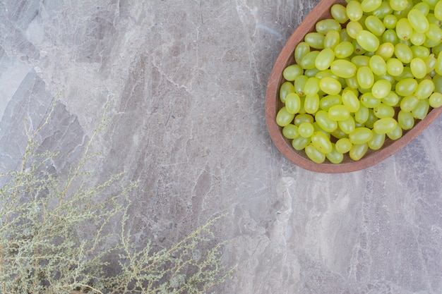 Racimo de uvas verdes en un tazón de madera.