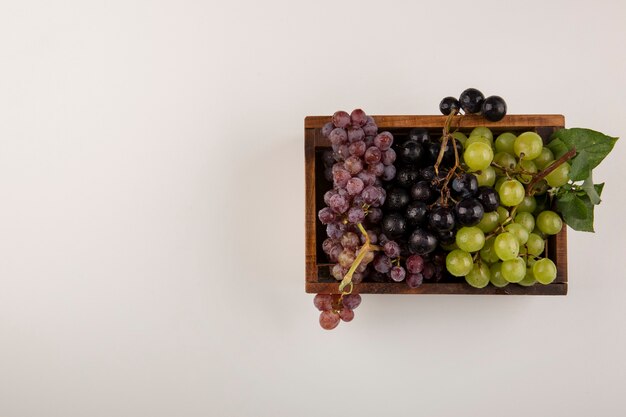 Racimos de uva verde y roja en una caja de madera en el centro