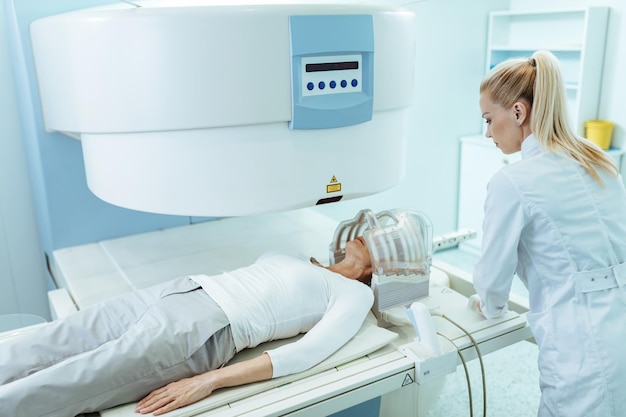 Foto gratuita radiólogo femenino y paciente maduro durante el examen de tomografía computarizada de la cabeza en la clínica