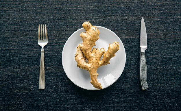 Foto gratuita raíz de jengibre en un plato y cubiertos minimalismo conceptual endecha plana