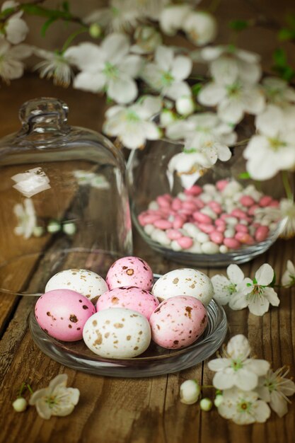 Rama de flores de primavera y coloridos huevos de caramelo rosa para pascua en rústico