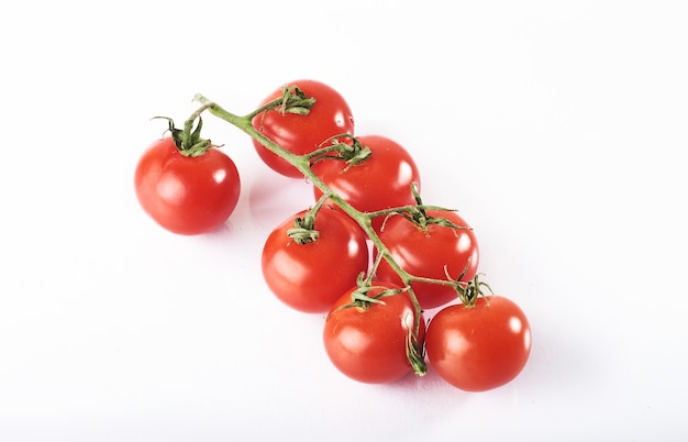 Rama de tomates orgánicos rojos sobre un fondo blanco.