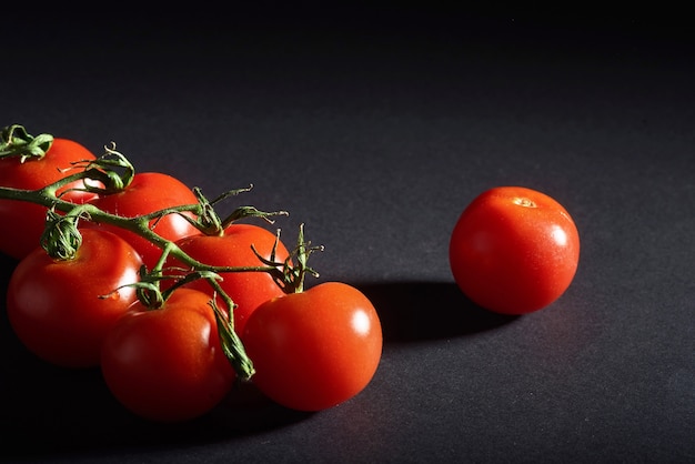 Rama de tomates orgánicos rojos sobre un negro