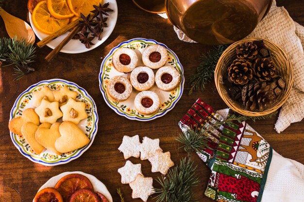 Ramas y conos de coníferas cerca de galletas y especias