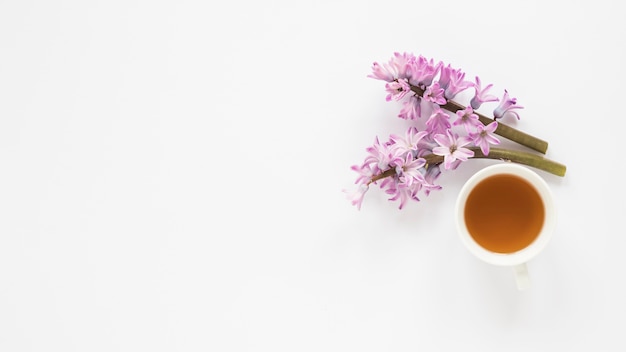 Ramas de flor morada con taza de té