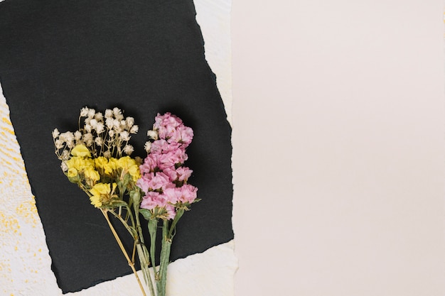 Ramas de flores brillantes con papel negro en la mesa