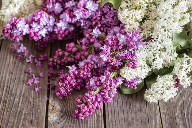 Ramas de lilas frescas en flor sobre una mesa de madera oscura.