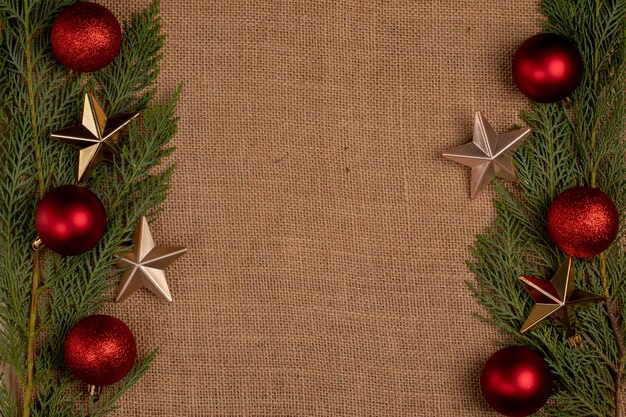 Ramas de roble verde con bolas rojas de Navidad y estrellas doradas en los dos lados.