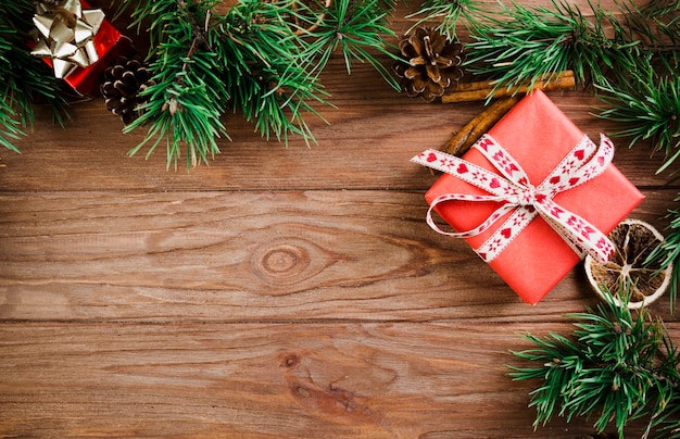 Ramita navideña y cajas de regalo en tablero de madera.