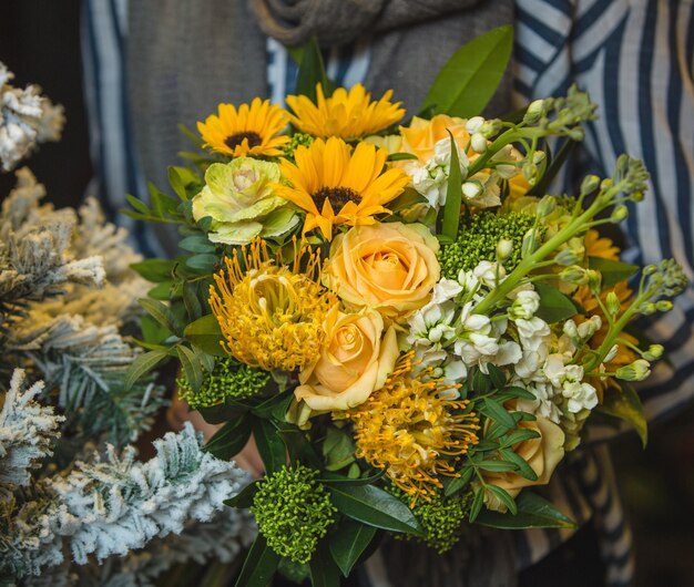 Un ramo amarillo de girasoles y rosas en manos de una dama