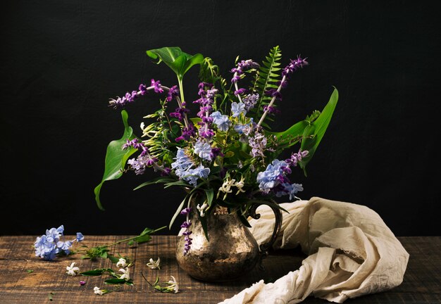 Ramo de flores azules y violetas en jarrón sobre mesa