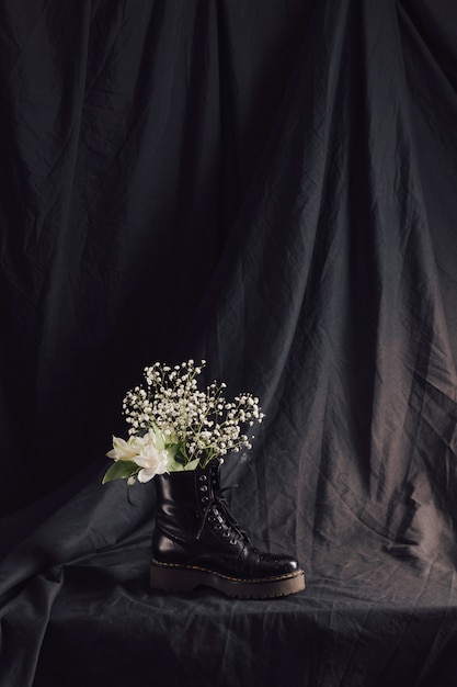 Ramo de flores blancas en bota de cuero oscuro.