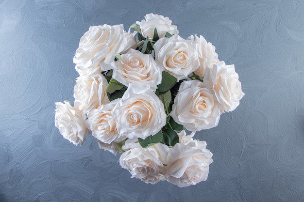 Un ramo de flores blancas en un cubo, sobre la mesa blanca.