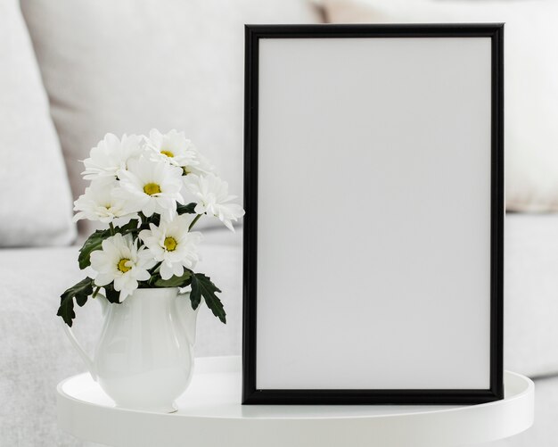 Ramo de flores blancas en un jarrón con marco vacío