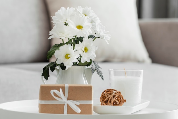 Ramo de flores blancas en un jarrón con regalo envuelto