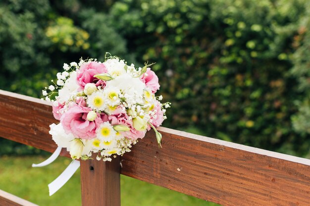 Ramo de flores de boda atado en barandilla de madera en el parque