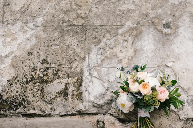 Ramo de flores de color rosa y blanco se encuentra ante un muro de hormigón