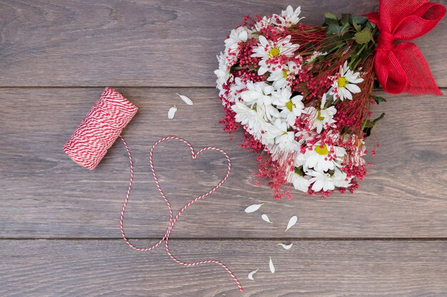 Ramo de flores con corazón de cuerda en mesa de madera