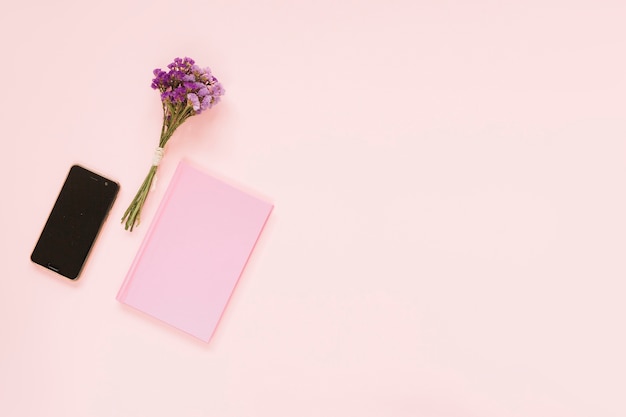 Foto gratuita ramo de flores de lavanda; teléfono celular y diario en el contexto rosado