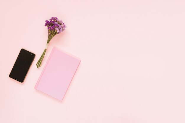 Ramo de flores de lavanda; teléfono celular y diario en el contexto rosado