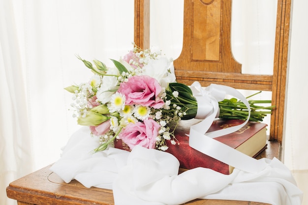 Ramo de flores en libro con bufanda en silla de madera