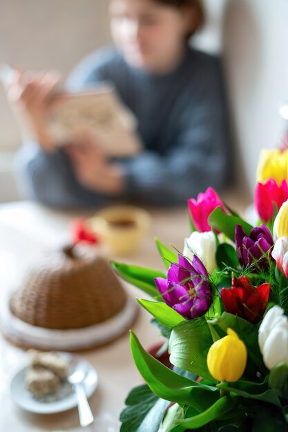 Ramo de flores con una niña escribiendo sobre la mesa. Cocina