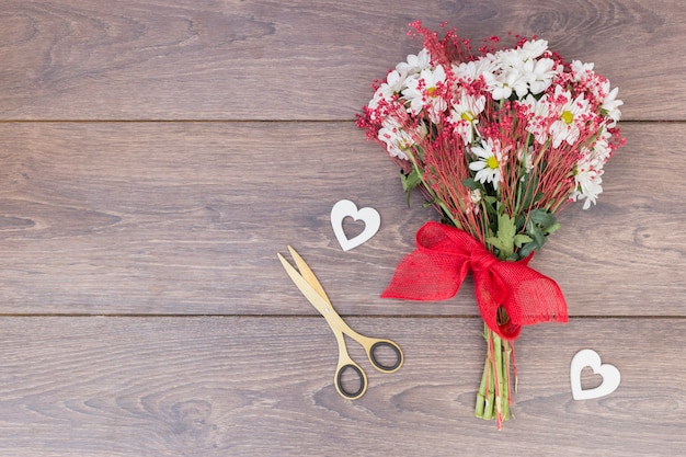 Ramo de flores con pequeños corazones en mesa.