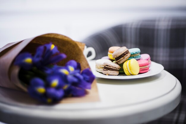 Ramo de flores y plato de macarrones en mesa blanca