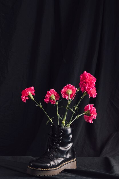 Ramo de flores rosas en bota oscura.