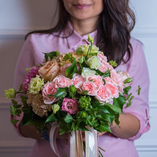 Ramo de flores rosas rosadas en manos de una mujer