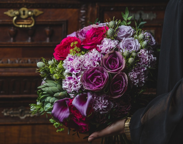 Foto gratuita ramo de flores sujeto por una mujer en la puerta