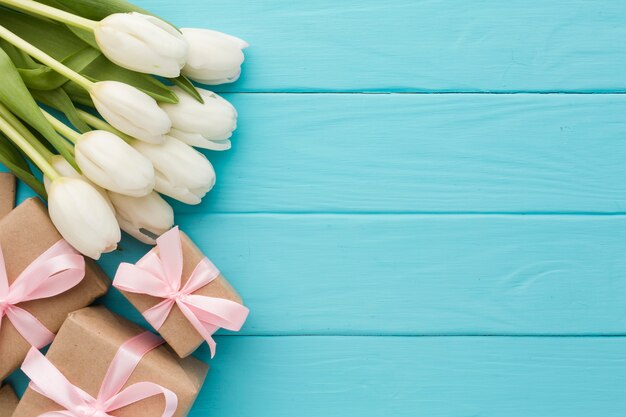 Ramo de flores de tulipán con regalos sobre fondo de madera