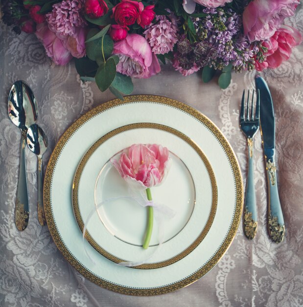 Ramo de flores y tulipán rosa dentro de platos blancos.