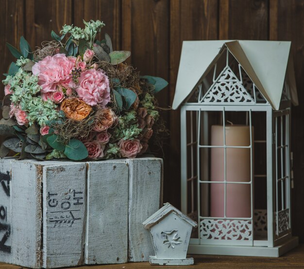 Ramo de flores, vela en la jaula y caja de madera rústica