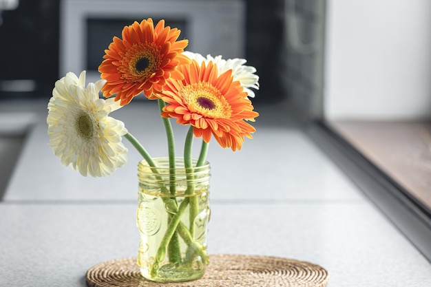 Foto gratuita un ramo de gerberas naranjas y blancas en un jarrón en el interior de una cocina