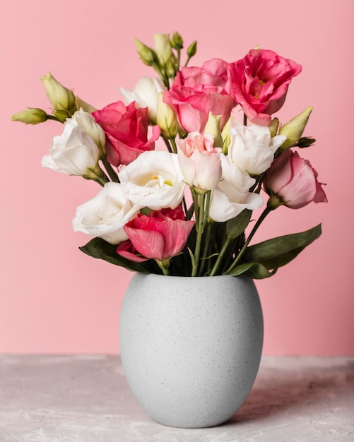 Ramo de rosas en un jarrón junto a una pared rosa