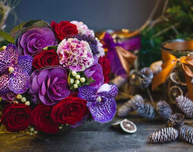 Un ramo de rosas rojas, flores de color rosa y morado con hojas en la mesa de navidad