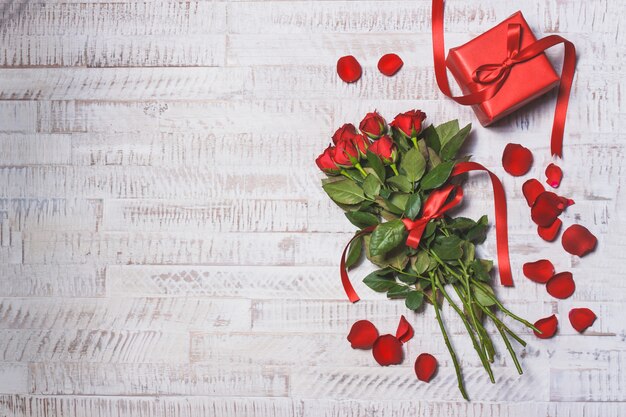 Ramo de rosas sobre una mesa de madera con un regalo