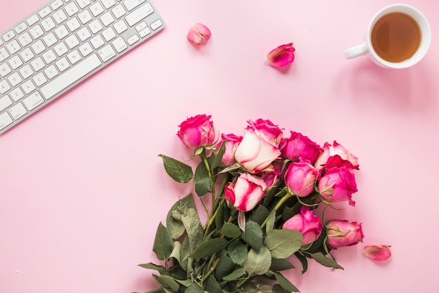 Foto gratuita ramo de rosas con taza de té y teclado.