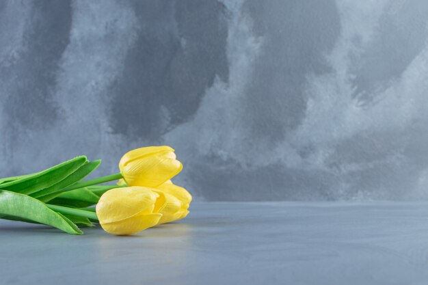 Ramo de tulipanes amarillos, sobre la mesa blanca.