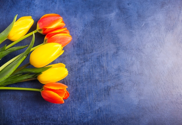 Ramo de tulipanes brillantes en mesa azul