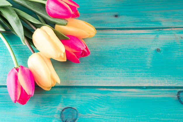 Ramo de tulipanes brillantes en mesa de madera