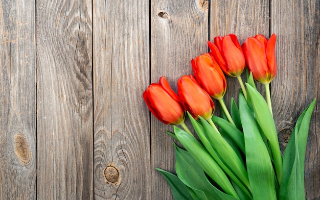 Ramo de tulipanes rojos en una vista superior de fondo de madera