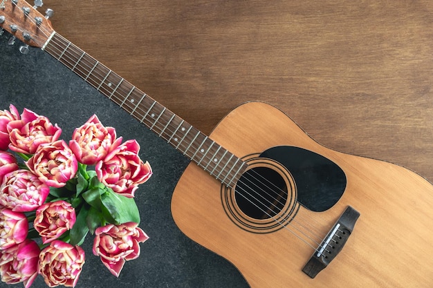Foto gratuita ramo de tulipanes rosados y guitarra acústica en un fondo de madera vista superior